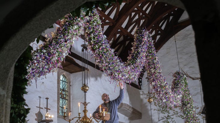 A floral garland made of pink and purple flowers hanging within the Tudor Great Hall at Cotehele